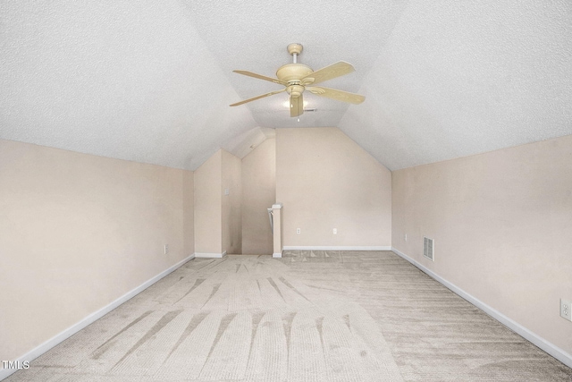 bonus room with ceiling fan, a textured ceiling, light carpet, and lofted ceiling