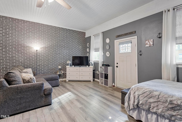 bedroom with ceiling fan, light hardwood / wood-style flooring, brick wall, and ornamental molding