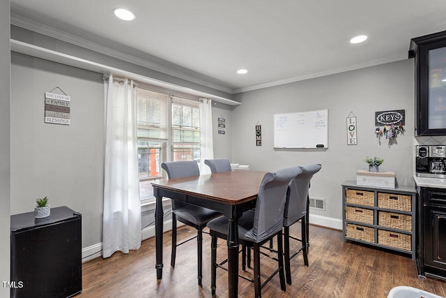 dining space featuring ornamental molding and dark wood-type flooring