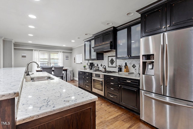 kitchen featuring light stone counters, stainless steel appliances, crown molding, sink, and light hardwood / wood-style flooring