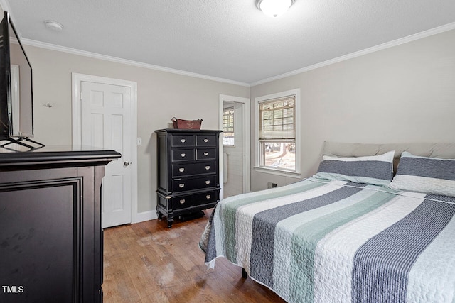 bedroom with hardwood / wood-style floors, a textured ceiling, and ornamental molding