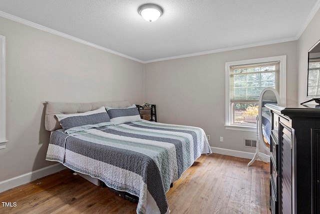 bedroom with crown molding, wood-type flooring, and a textured ceiling