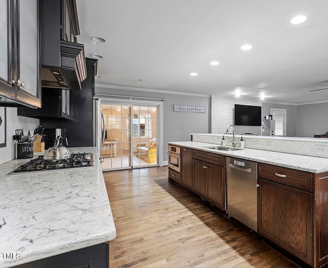 kitchen with light stone countertops, sink, stainless steel appliances, and wood-type flooring