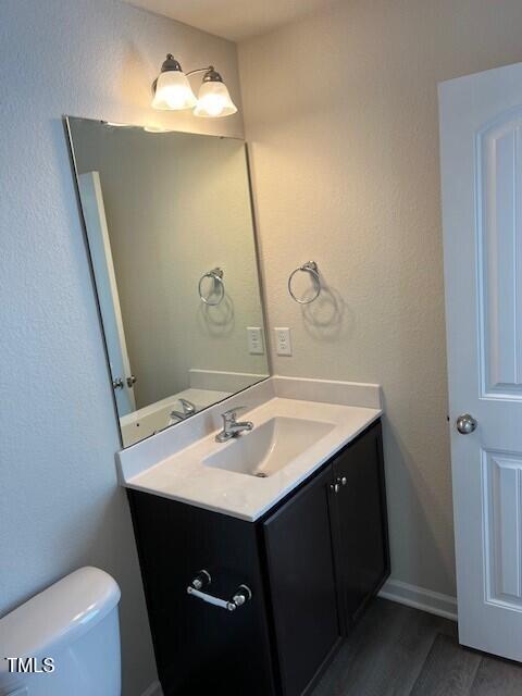 bathroom featuring toilet, vanity, and hardwood / wood-style floors