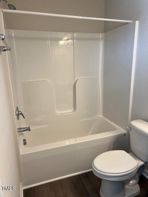 bathroom featuring bathing tub / shower combination, hardwood / wood-style flooring, and toilet