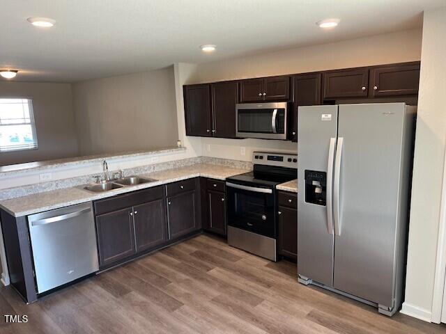 kitchen with sink, dark brown cabinetry, light hardwood / wood-style floors, and stainless steel appliances