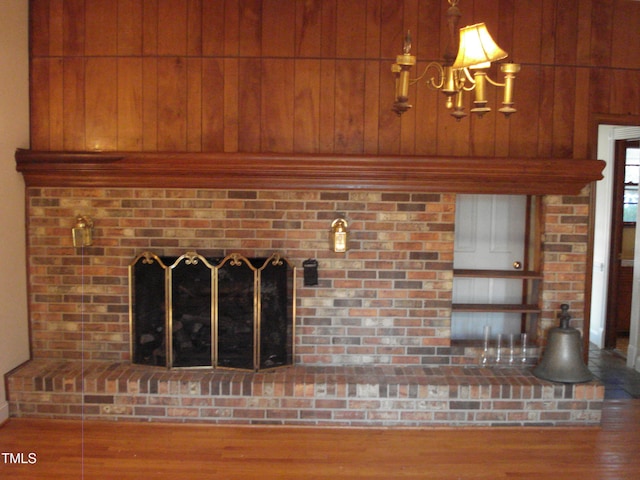 room details with a brick fireplace, wooden walls, and hardwood / wood-style floors