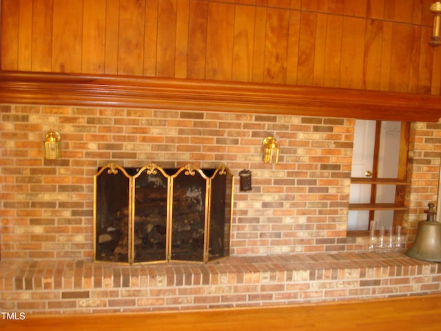 room details featuring wood walls, wood-type flooring, and a brick fireplace