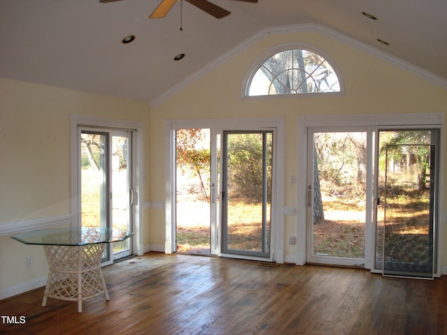 doorway with dark hardwood / wood-style floors, a healthy amount of sunlight, vaulted ceiling, and ornamental molding