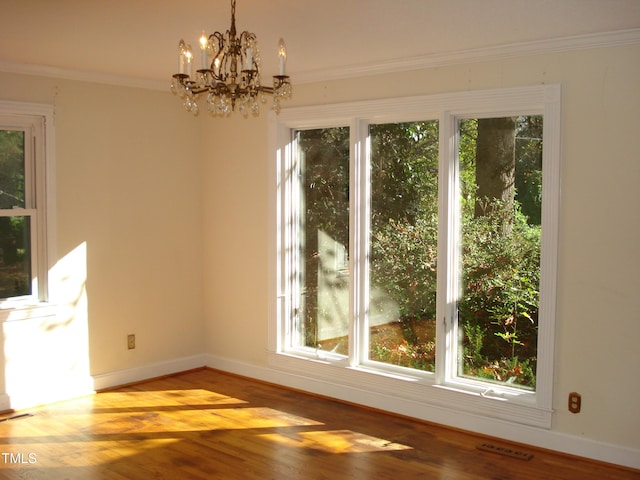 unfurnished dining area with light hardwood / wood-style floors, plenty of natural light, a notable chandelier, and ornamental molding