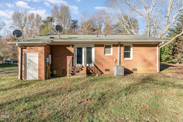 back of property with central air condition unit and a yard