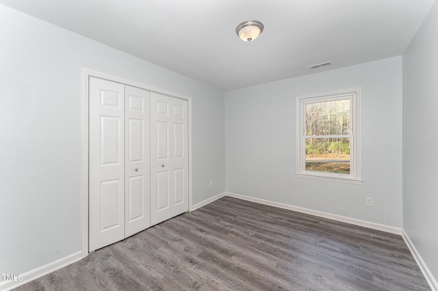 unfurnished bedroom featuring a closet and dark wood-type flooring