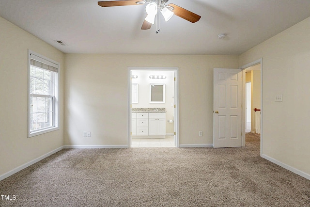 unfurnished bedroom featuring ceiling fan, light carpet, and ensuite bath