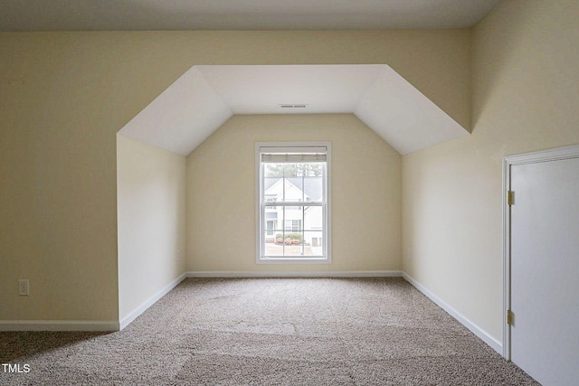 additional living space featuring vaulted ceiling and carpet flooring