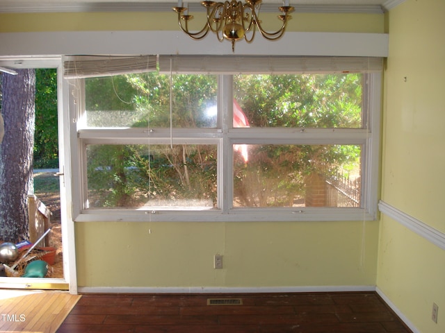 interior space featuring a wealth of natural light, a notable chandelier, ornamental molding, and dark hardwood / wood-style floors