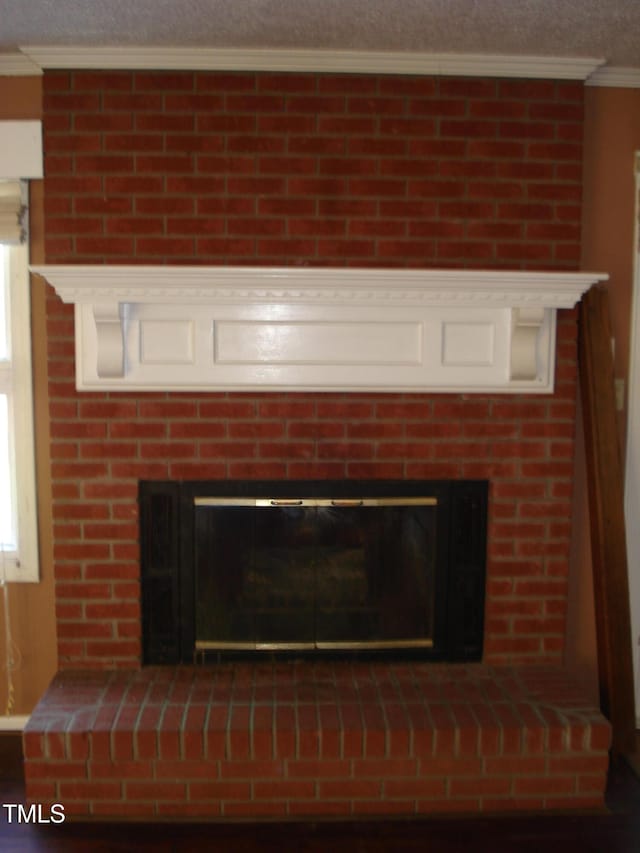 interior details with a fireplace, a textured ceiling, and crown molding