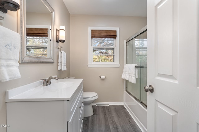 full bathroom with toilet, hardwood / wood-style floors, vanity, and combined bath / shower with glass door