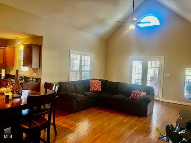 living room featuring light hardwood / wood-style flooring, high vaulted ceiling, plenty of natural light, and ceiling fan