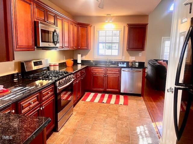 kitchen featuring dark stone counters, stainless steel appliances, light hardwood / wood-style floors, and sink