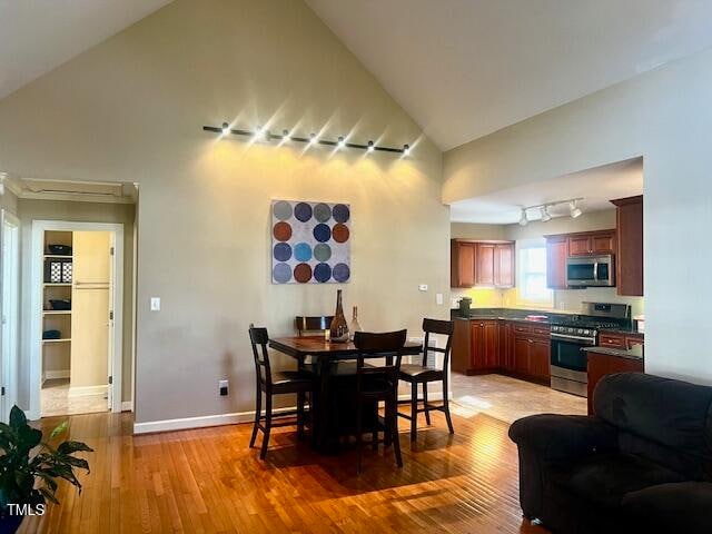 dining room with hardwood / wood-style floors and high vaulted ceiling