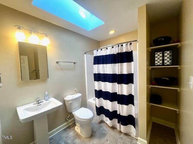 full bathroom with a skylight, sink, shower / bath combination with curtain, and toilet