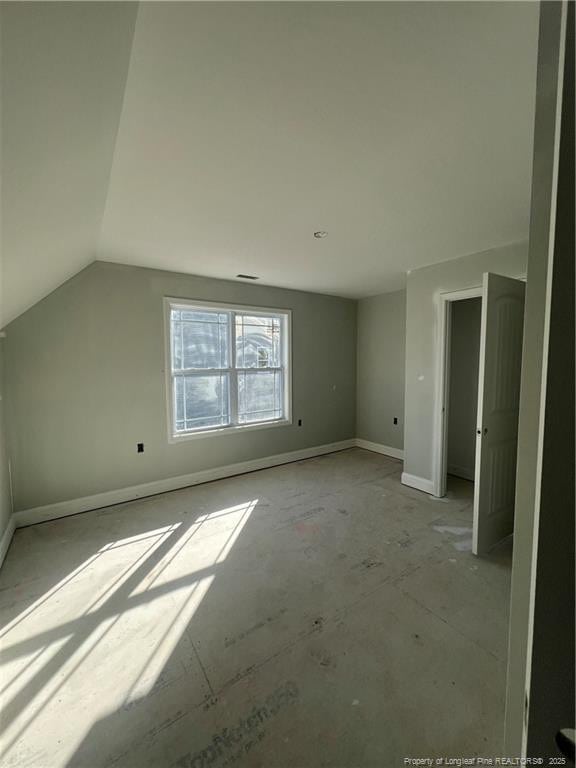 bonus room with vaulted ceiling and baseboards