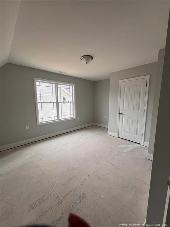 unfurnished bedroom featuring vaulted ceiling and baseboards