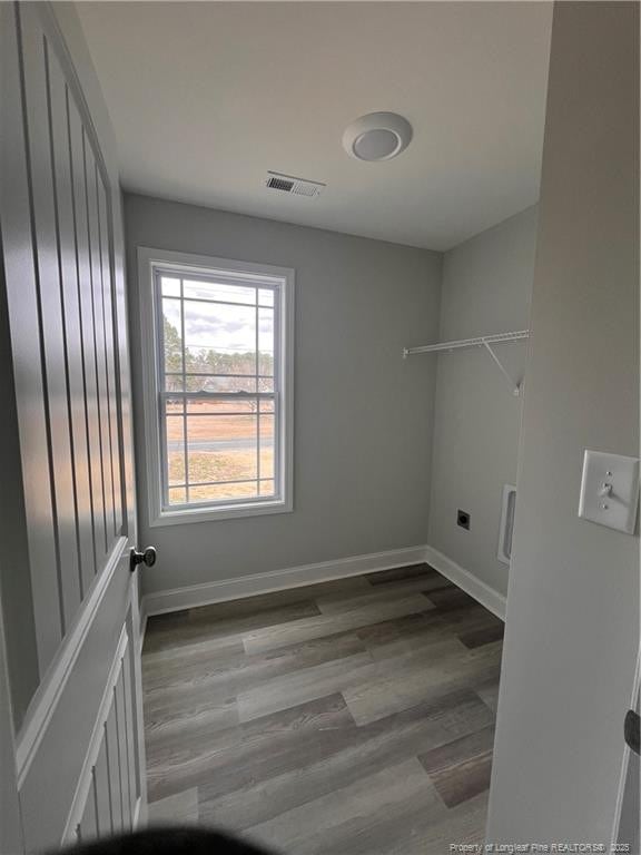 washroom featuring hookup for an electric dryer, laundry area, wood finished floors, visible vents, and baseboards