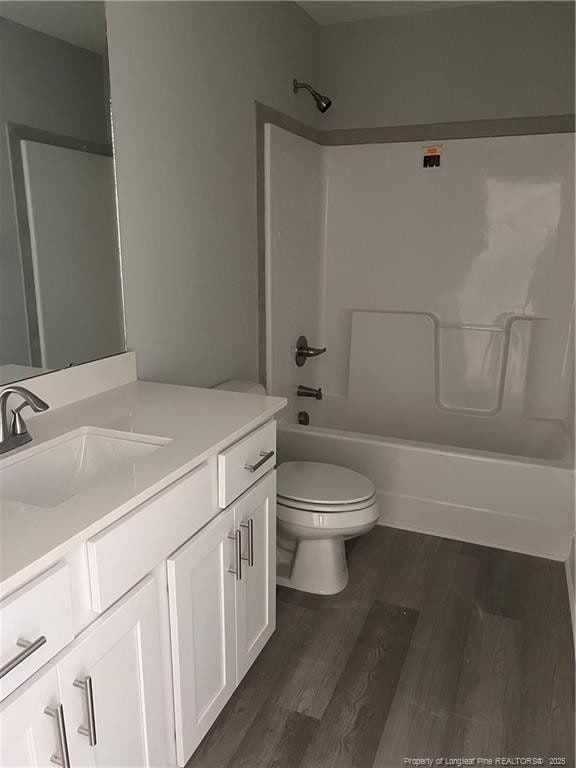 full bathroom featuring vanity, bathing tub / shower combination, wood finished floors, and toilet