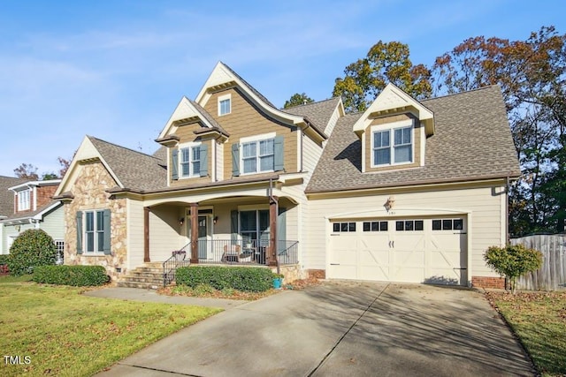 view of front of home with covered porch, a garage, and a front lawn