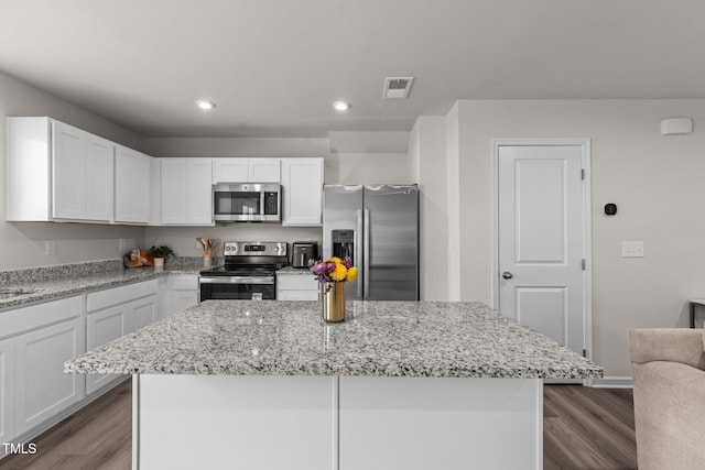 kitchen featuring white cabinetry, a kitchen island, light stone countertops, and appliances with stainless steel finishes