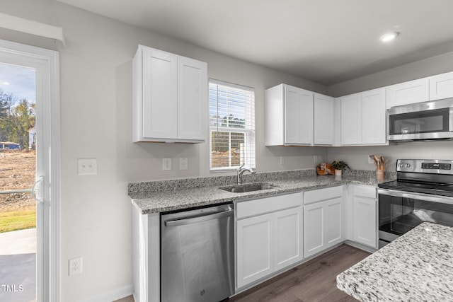 kitchen featuring light stone countertops, dark hardwood / wood-style flooring, stainless steel appliances, sink, and white cabinetry