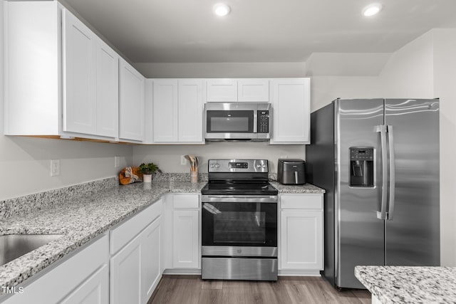 kitchen featuring white cabinetry, hardwood / wood-style floors, and appliances with stainless steel finishes