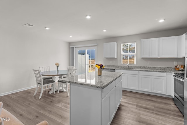 kitchen featuring white cabinets, light wood-type flooring, a center island, and stainless steel appliances