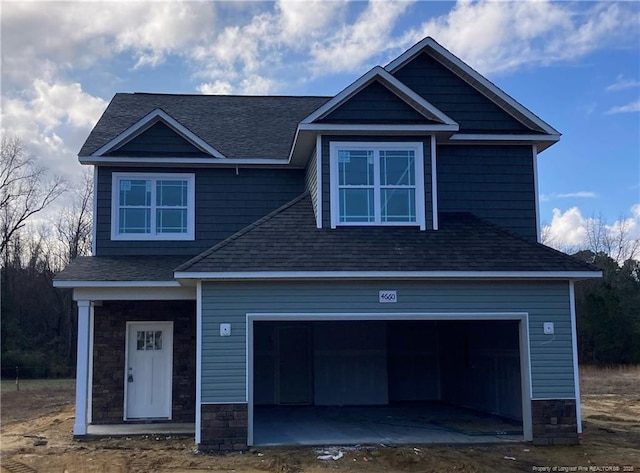 craftsman-style house featuring a garage, stone siding, and a shingled roof