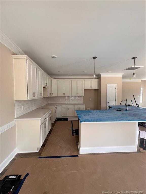 kitchen featuring decorative light fixtures, crown molding, decorative backsplash, white cabinetry, and baseboards