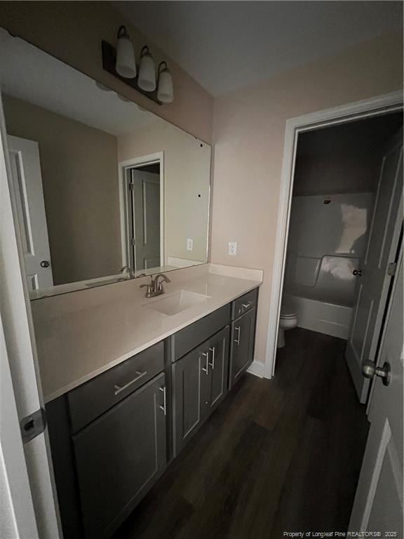 bathroom with toilet, baseboards, wood finished floors, and vanity