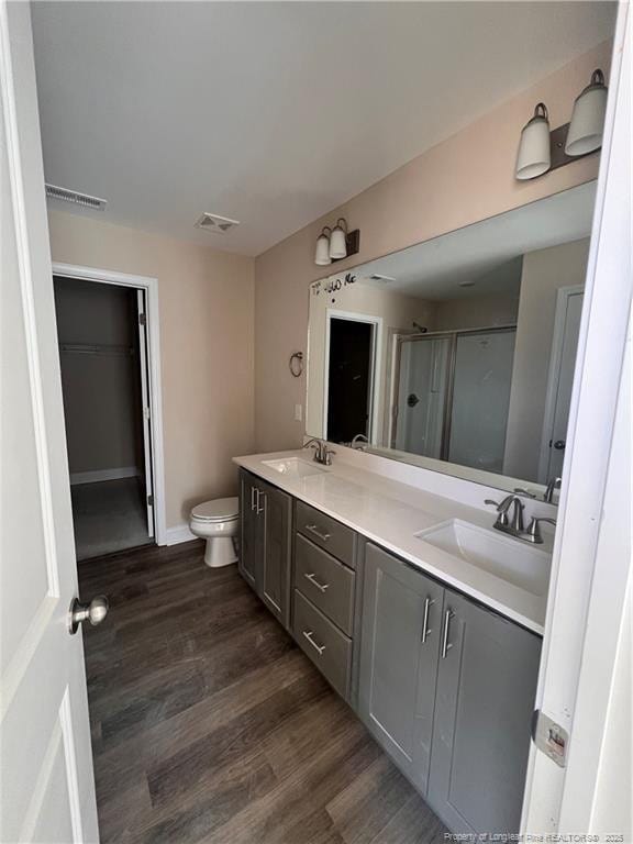 bathroom with double vanity, wood finished floors, a stall shower, and a sink