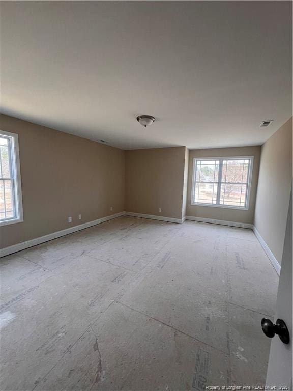 unfurnished room featuring visible vents, baseboards, and a wealth of natural light