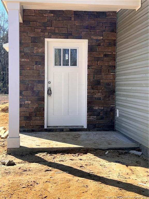 entrance to property featuring stone siding and brick siding