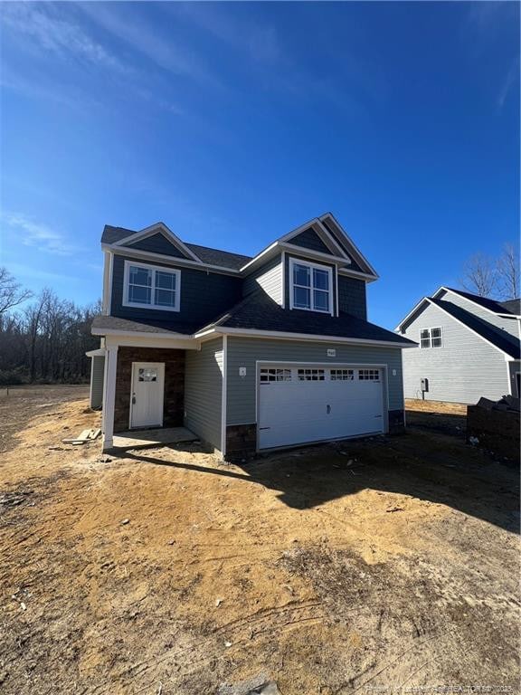 view of front of property with a garage, dirt driveway, and stone siding