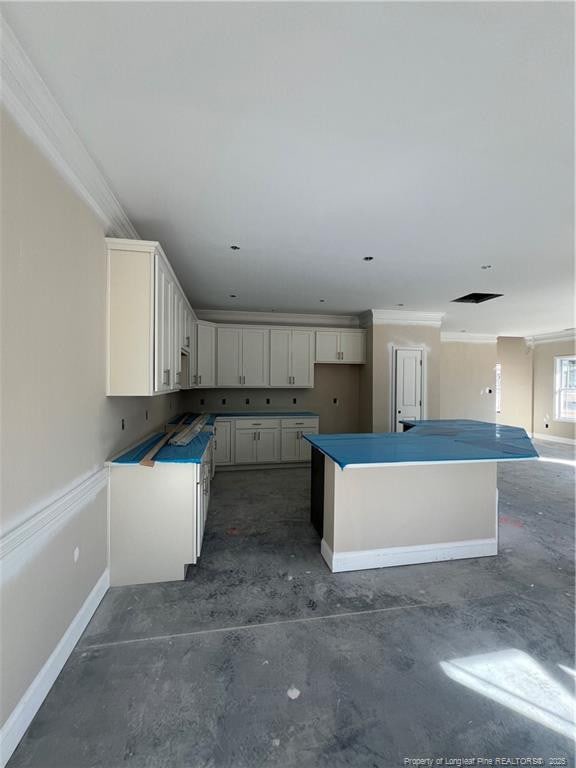 kitchen with concrete flooring, ornamental molding, and white cabinets