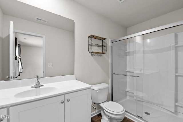 bathroom with vanity, toilet, hardwood / wood-style floors, and a shower with door