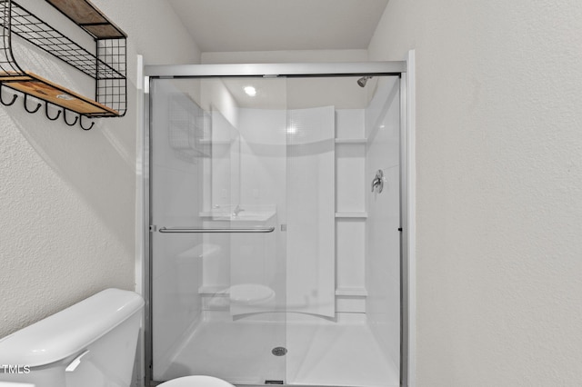 bathroom with a shower with door and toilet