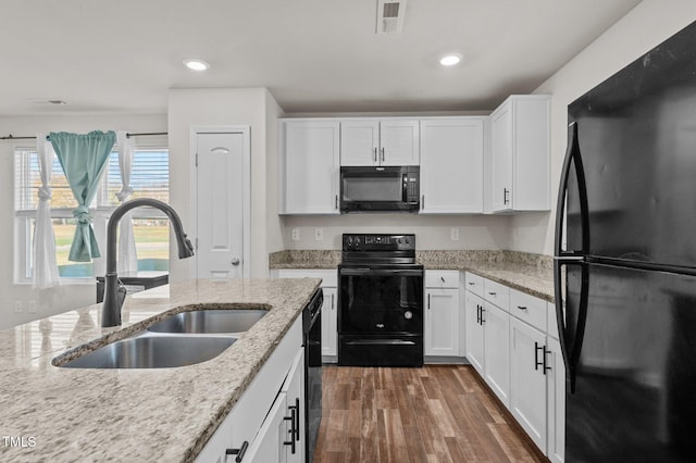 kitchen with sink, black appliances, white cabinets, and light stone counters