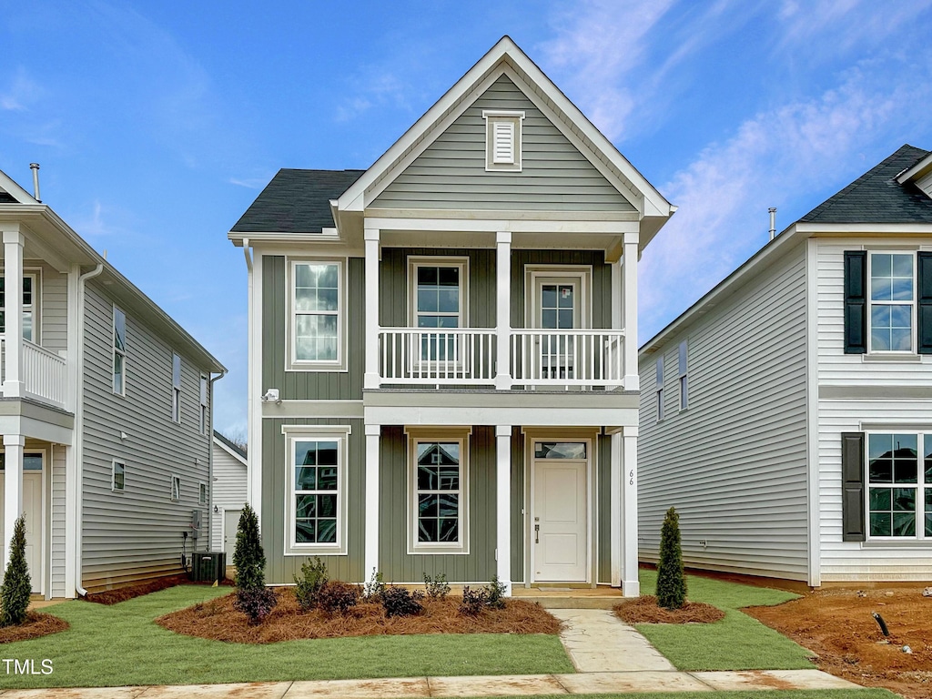 view of front of home with a balcony, a front lawn, and central air condition unit