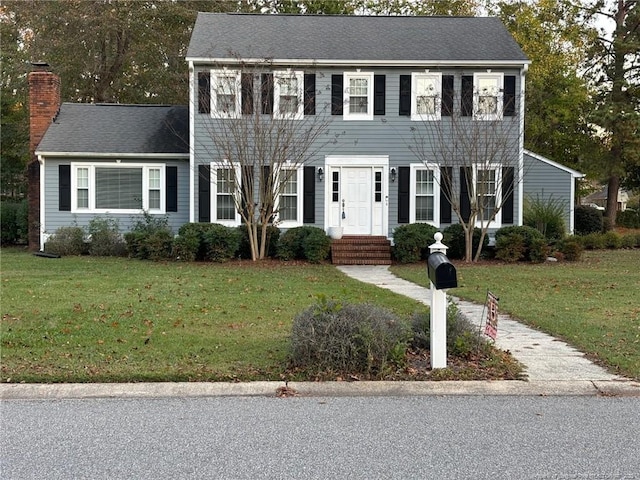 colonial inspired home featuring a front lawn