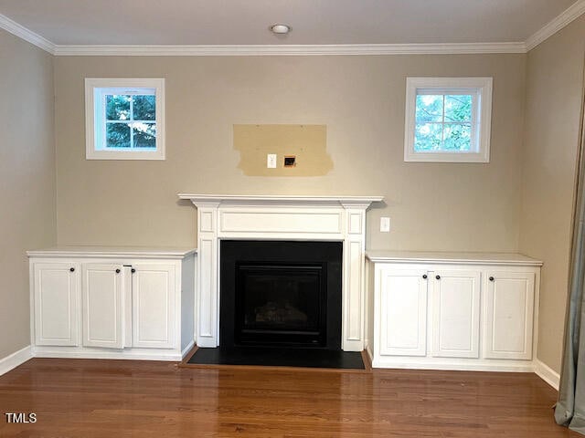 unfurnished living room with ornamental molding, dark wood-type flooring, and a healthy amount of sunlight