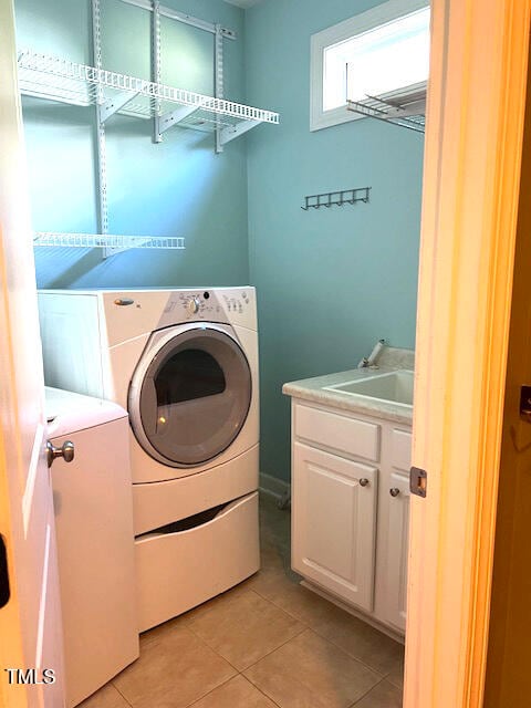 laundry room featuring cabinets, light tile patterned flooring, sink, and washing machine and clothes dryer