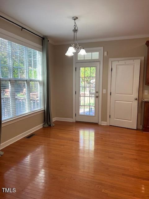 entryway featuring a chandelier, light hardwood / wood-style floors, and crown molding